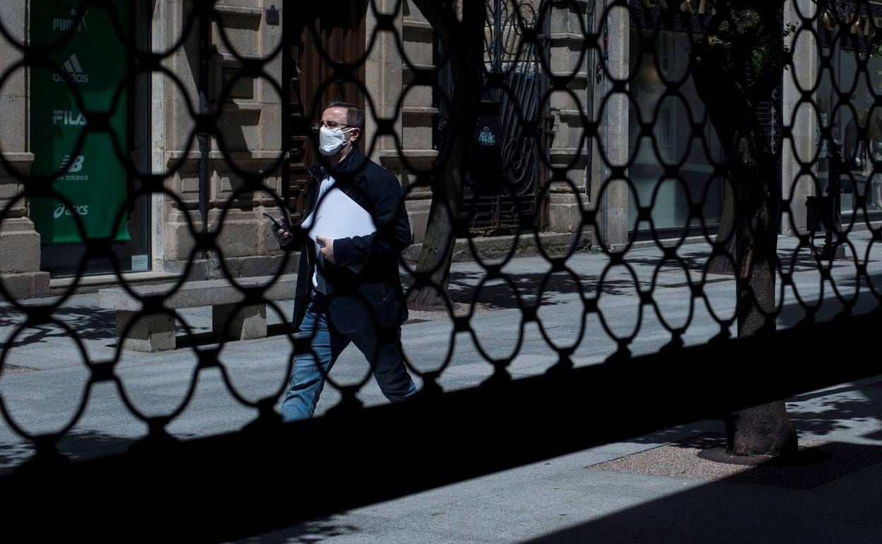 Un hombre, con mascarilla, pasa ante un establecimiento cerrado en pleno estado de alarma por coronavirus.