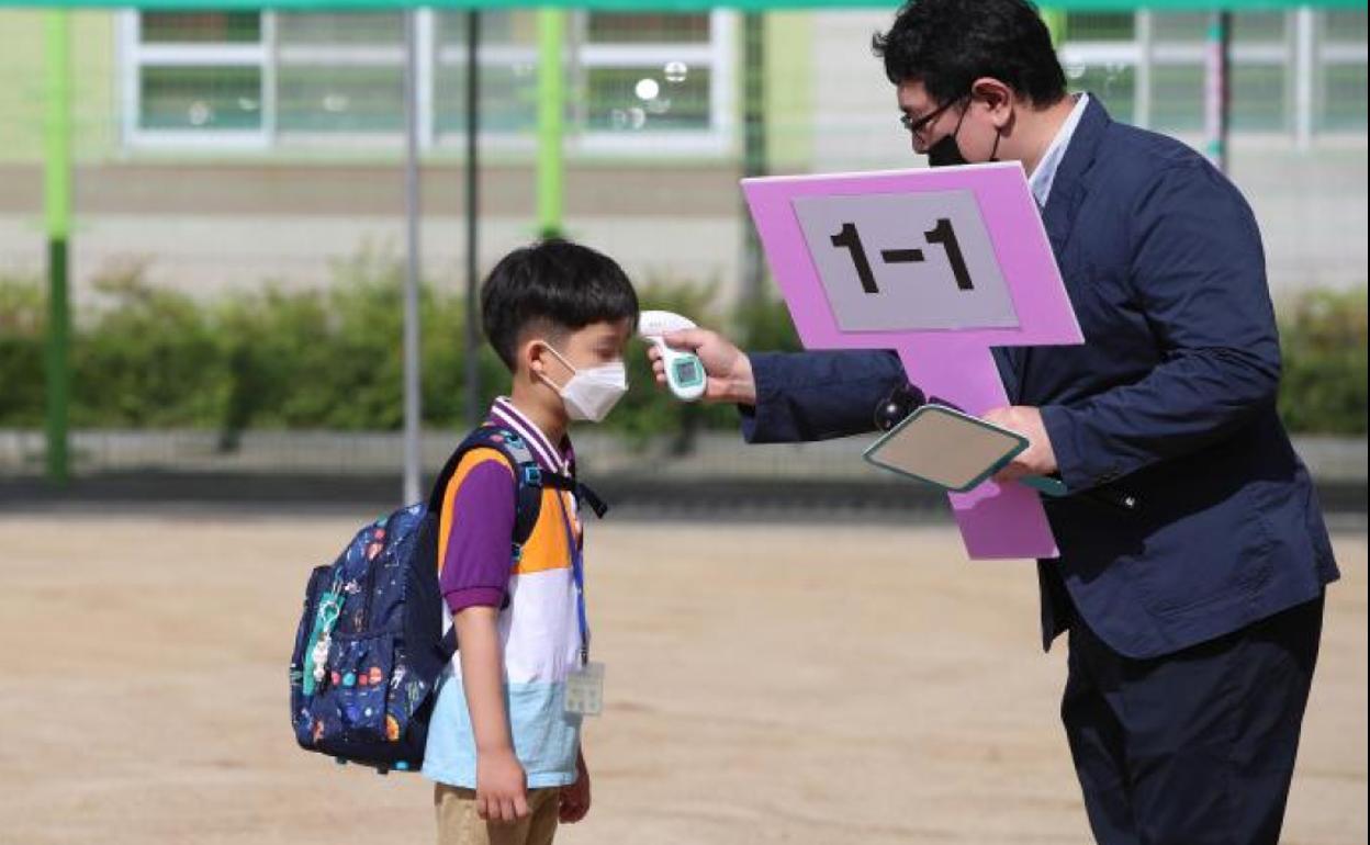 Toman la tempertura a un niño antes de entrar a un colegio en Corea del Sur. 