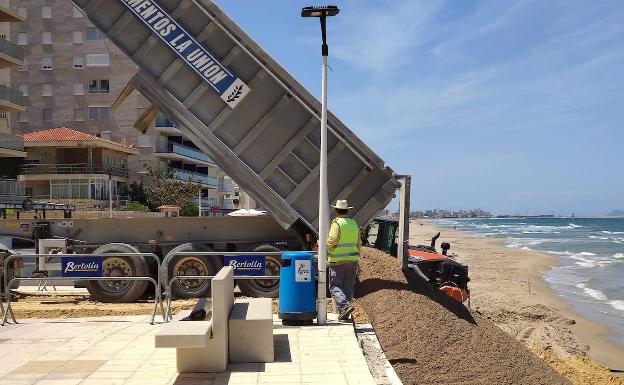 Un camión depositando arena en la playa de Bellreguard. 