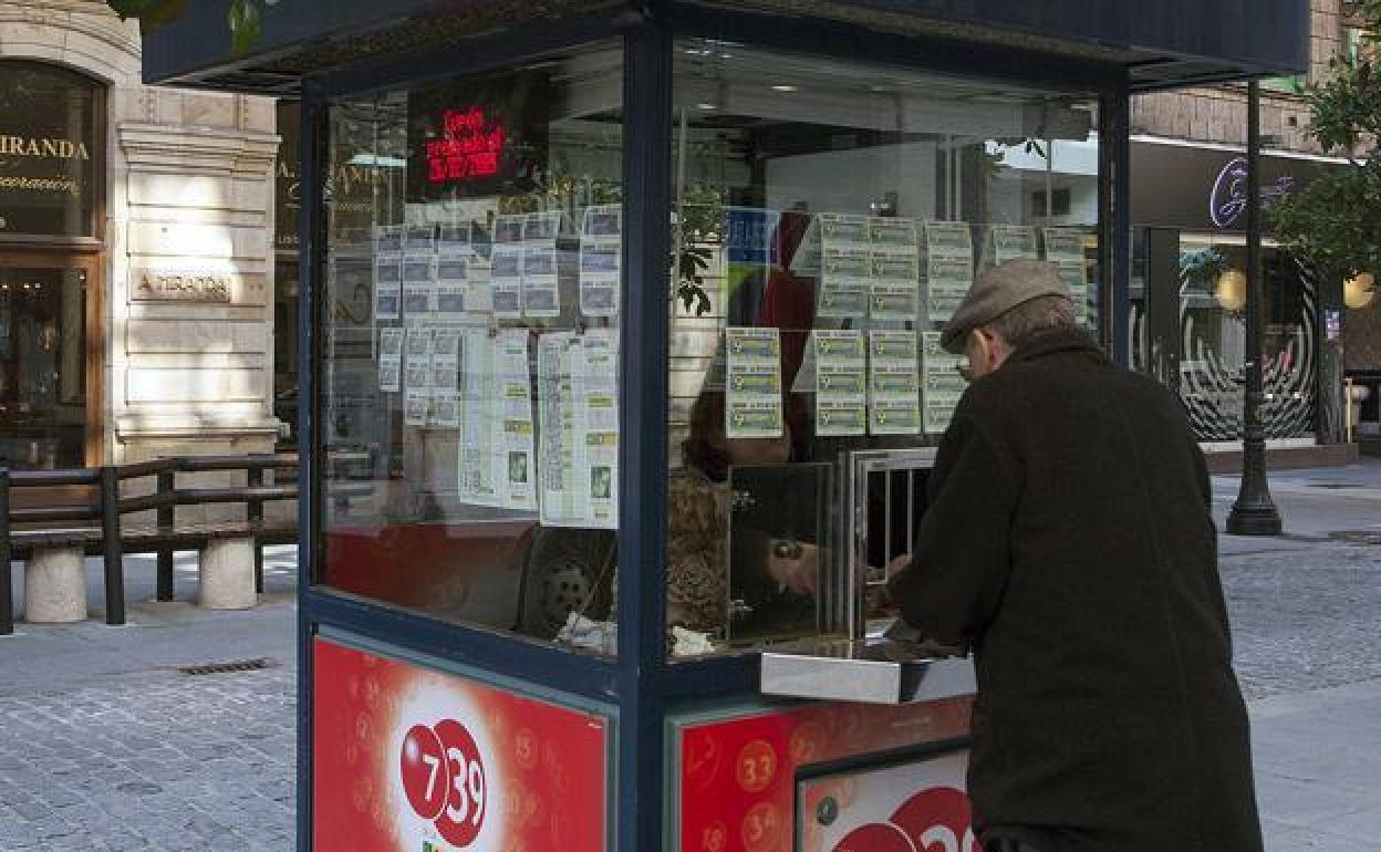 Un hombre compra un cupón en un quiosco de la ONCE.