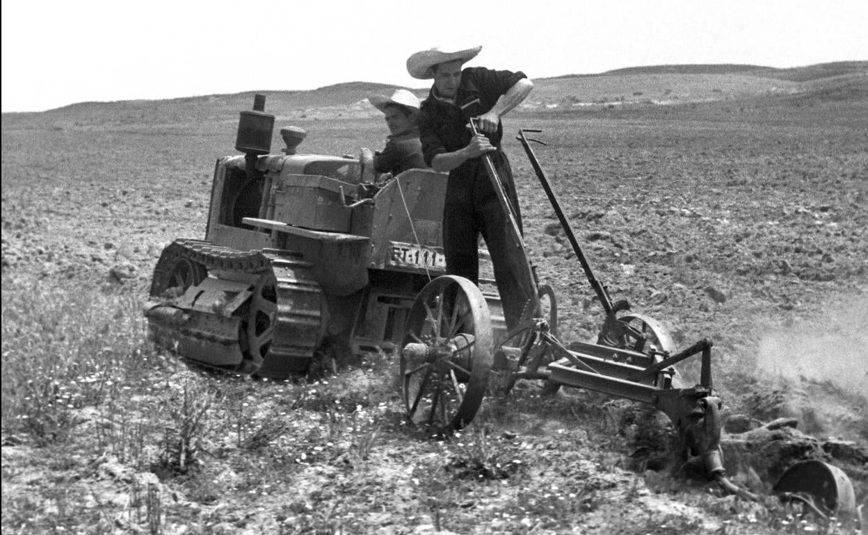 Dos agricultores usan un tractor para un ensayo de cultivo mecánico en la década de los 40.