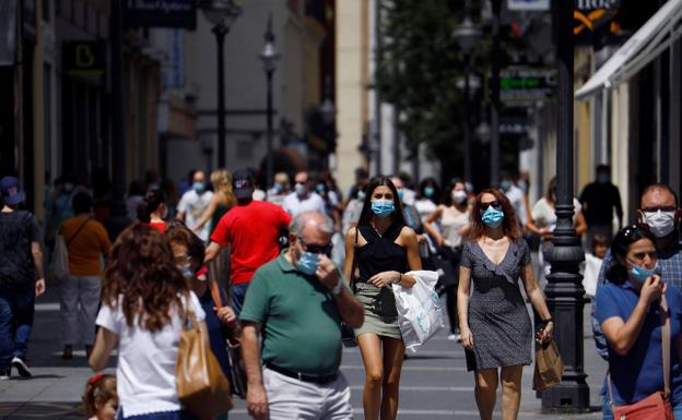 Gente protegida con mascarilla pasea por una calle de Córdoba.