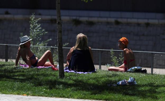 Tres mujeres toman el sol en un parque. 