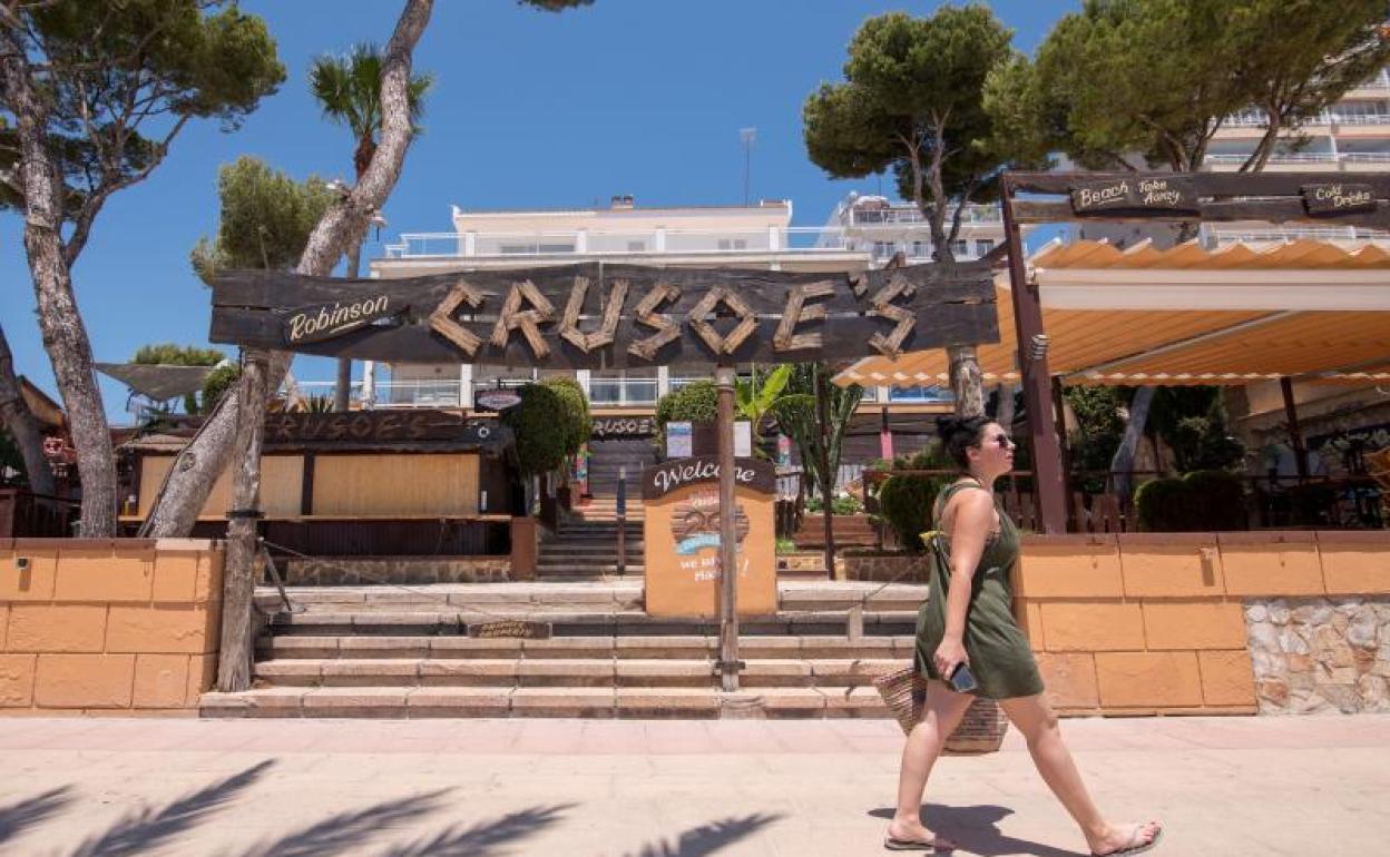 Una mujer pasea frente a una terraza en Magalluf, donde casi todos los negocios permanecen cerrados a la espera de la llegada de turistas británicos. 