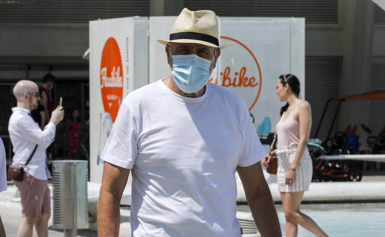 Dos personas pasean con mascarilla por la Ciudad de las Ciencias mientras una pareja sin esta protección se hace fotos.