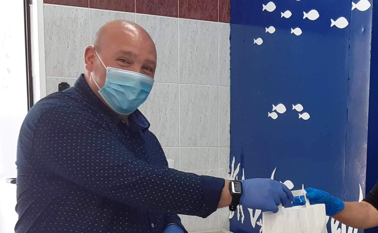 El alcalde de Turís repartiendo material a los comercios. 