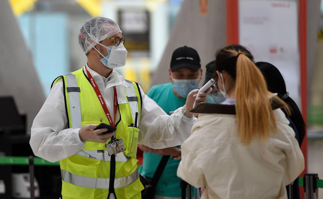 Un empleado del aeropuerto de Barajas toma la temperatura a una pasajera. 