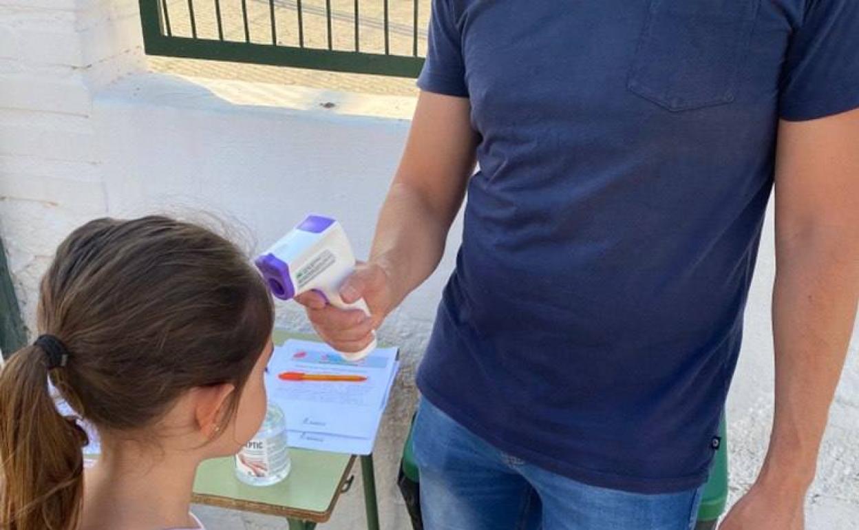 Un monitor toma la temperatura a una alumna del programa. 