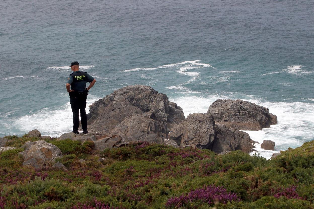 Un agente de la Guardia Civil mira entre las rocas. 