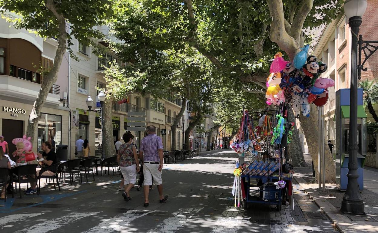 Una terraza y un puesto de globos y juguetes de la calle Marqués de Campo. 