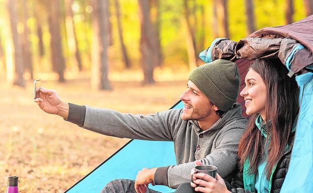 Una pareja acampando en una zona boscosa. 