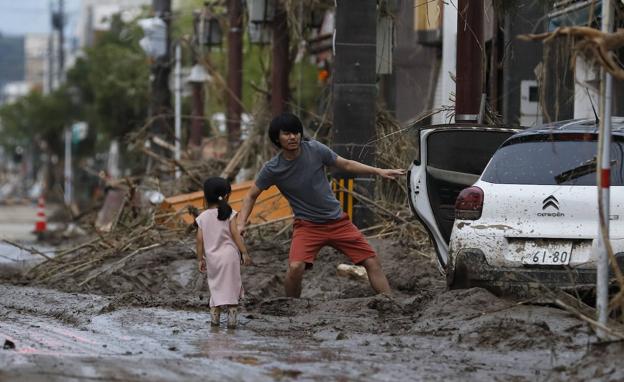 Un hombre y su hija intentan salir del lodo en Hitoyoshi. 