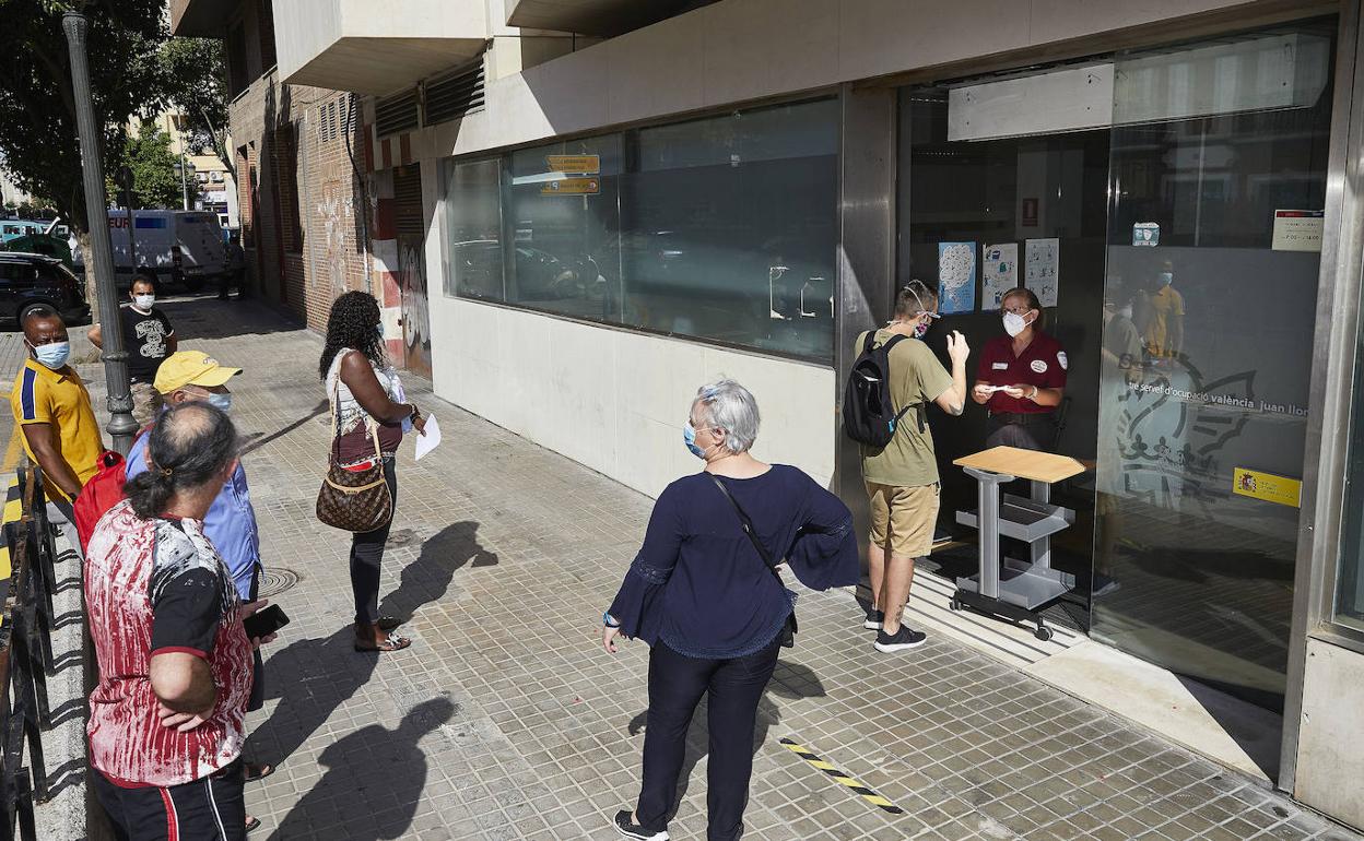 Varias personas esperan en la puerta de una oficina del SEPE en Valencia. 