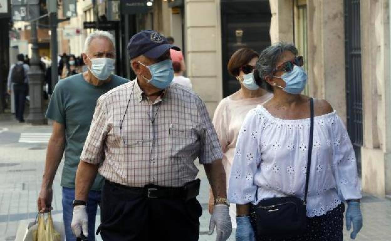 Dos personas caminan por Valencia con mascarilla.