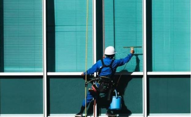 Un trabajador limpia ventanas en un edificio. 