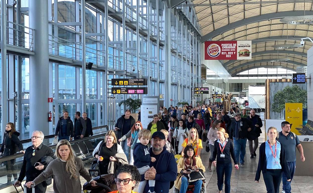 Cientos de viajeros caminan por la terminal principal del aeropuerto de Alicante-Elche. 