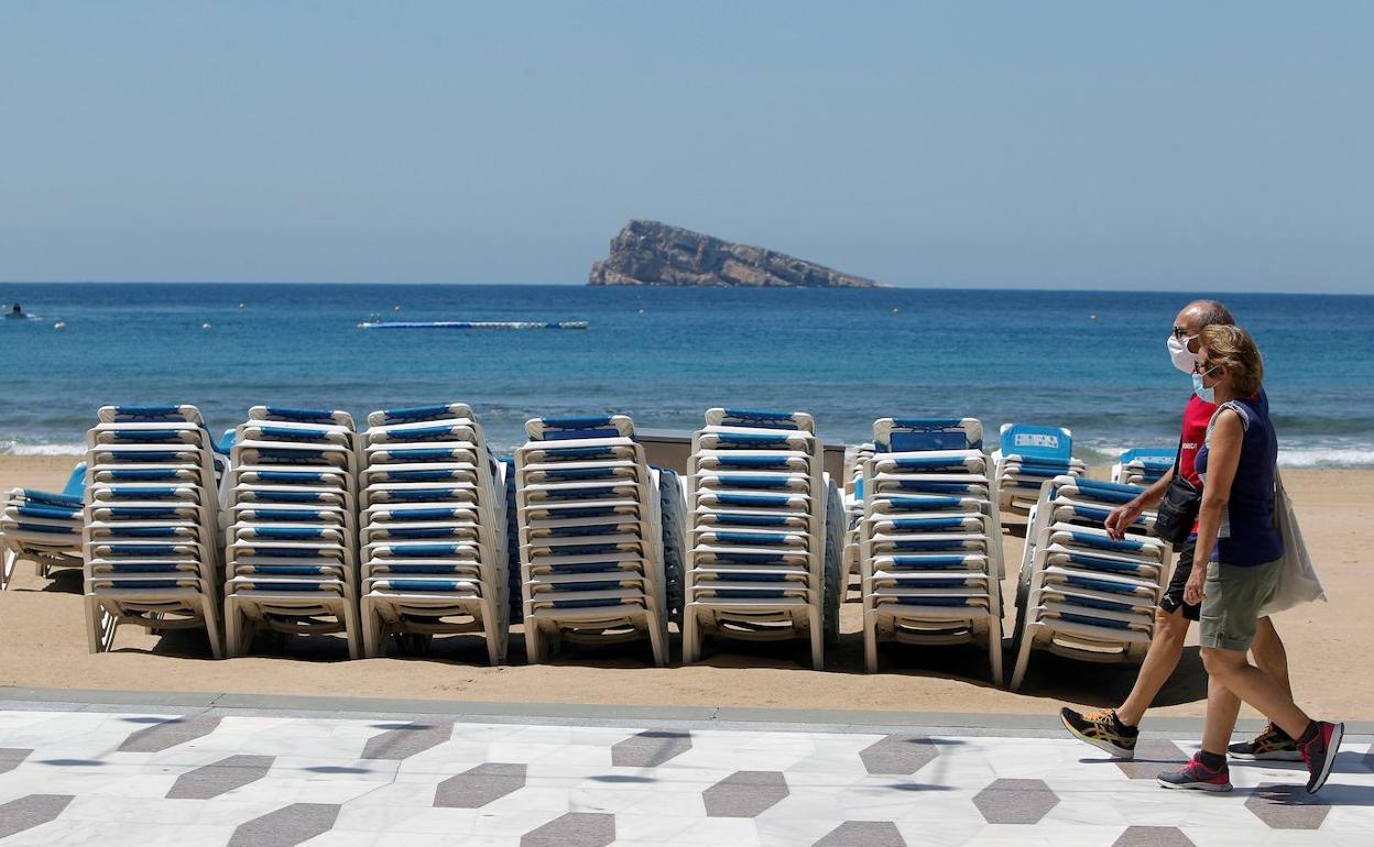 Una pareja pasea por  la playa de Benidorm. 