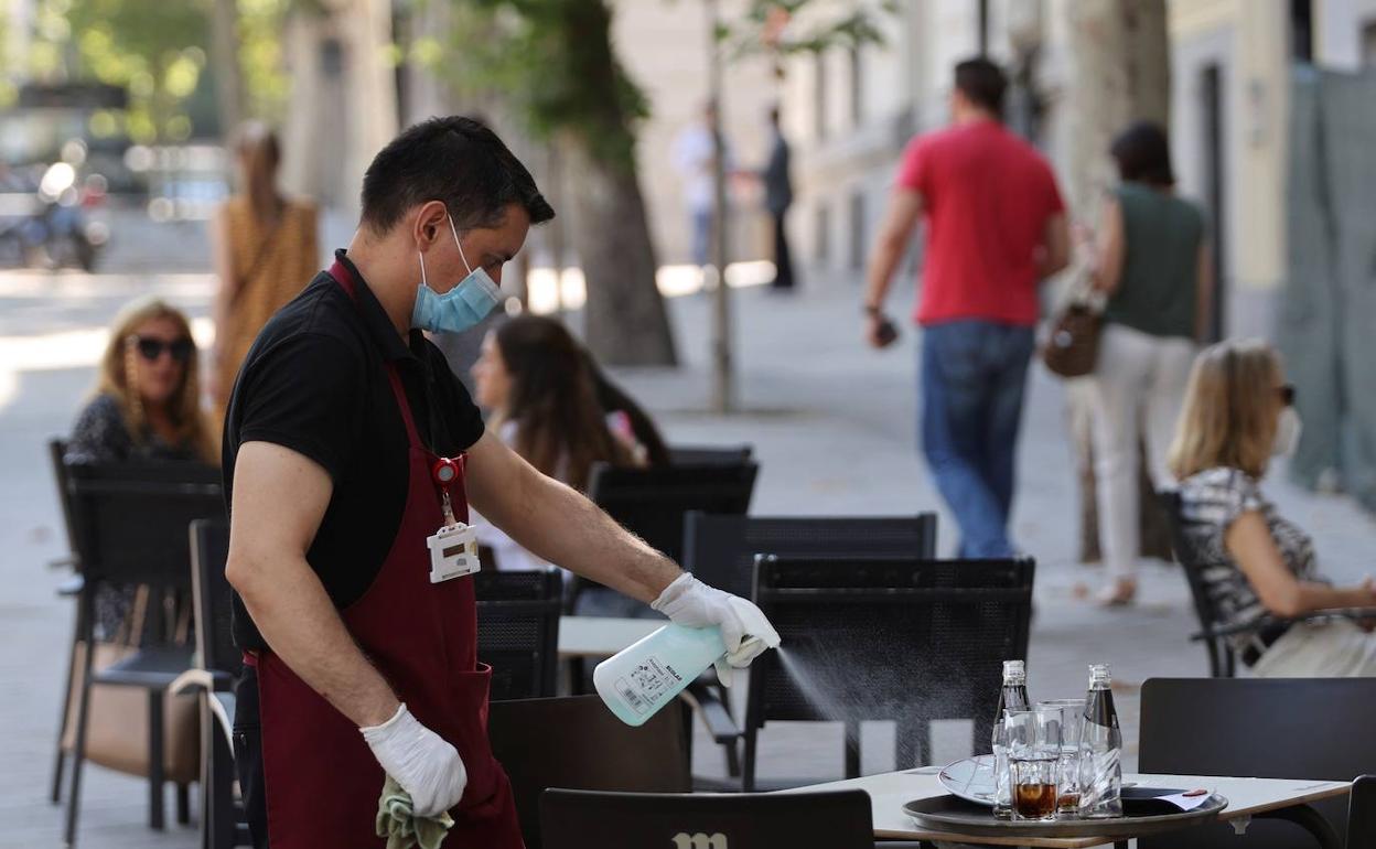 Un camarero limpia una mesa en una terraza de Madrid. 