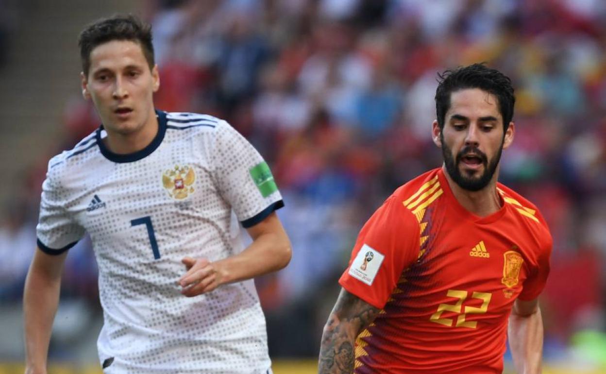 Daler Kuzyaev persigue a Isco durante un partido con España. 