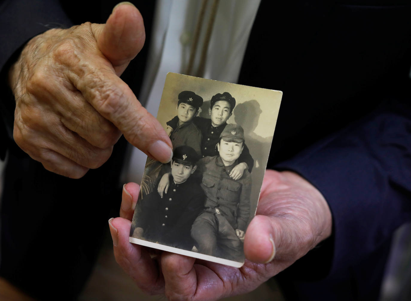 Tanaka, sobreviviente del bombardeo atómico, muestra su foto con sus compañeros de escuela tomada en marzo de 1941