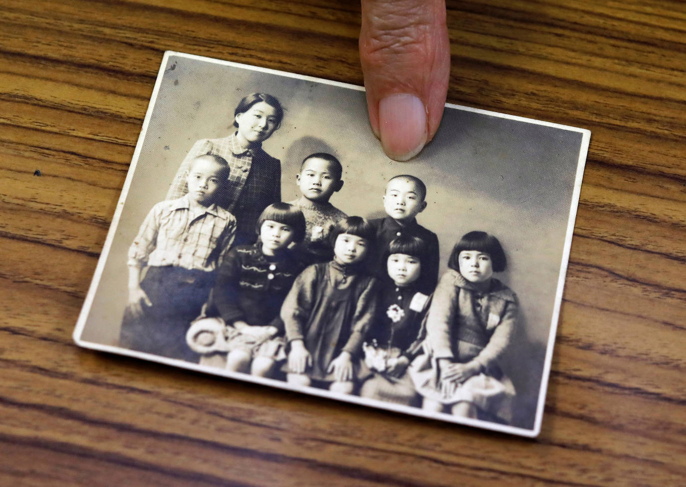 Terumi Tanaka, sobreviviente, muestra su foto con sus compañeros de escuela y un maestro de la Escuela Primaria Irabayashi tomada en marzo de 1941