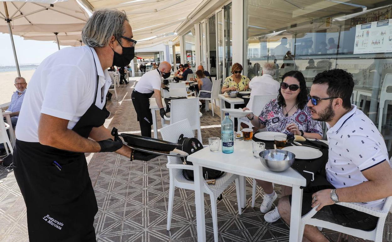 Empleado en un restaurante en la playa de Valencia atiende a los clientes. 