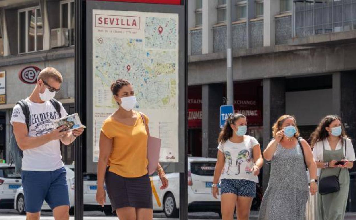 Un grupo de turistas pasea con mascarilla por Sevilla.