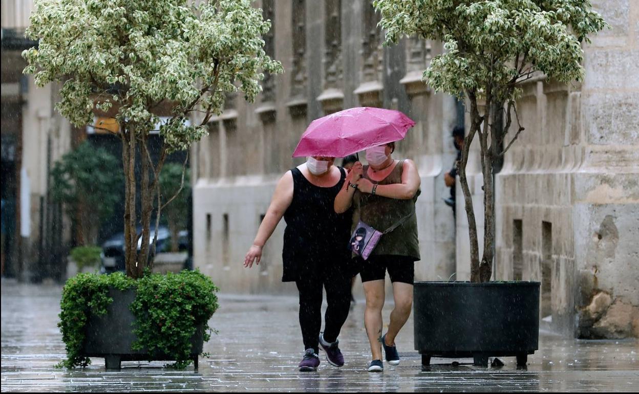 Dos personas caminan bajo la lluvia en Valencia. 