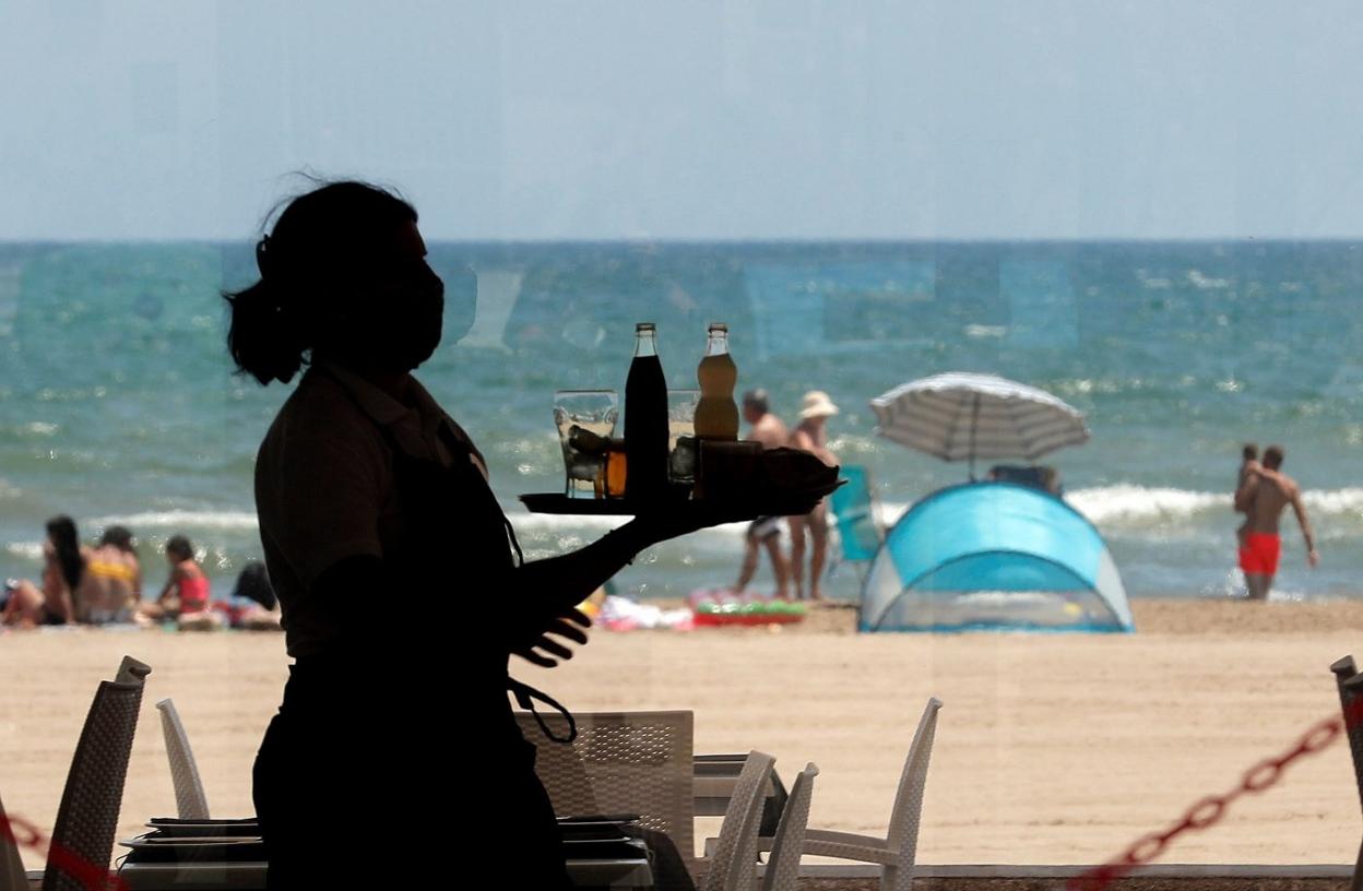 Una camarera sirve en un bar de la zona de la playa de Valencia. EFE/Kai Försterling