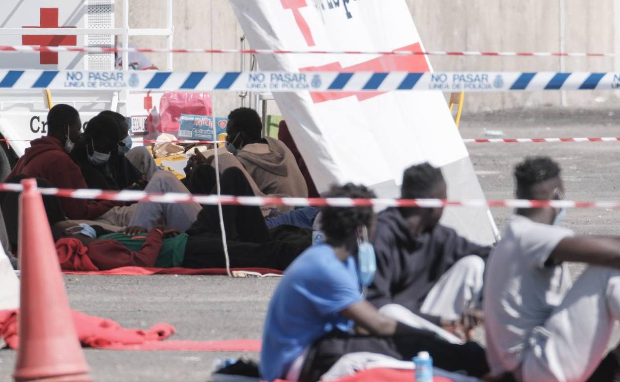 Varios inmigrantes descansan en el muelle de Arguineguín (Gran Canaria).