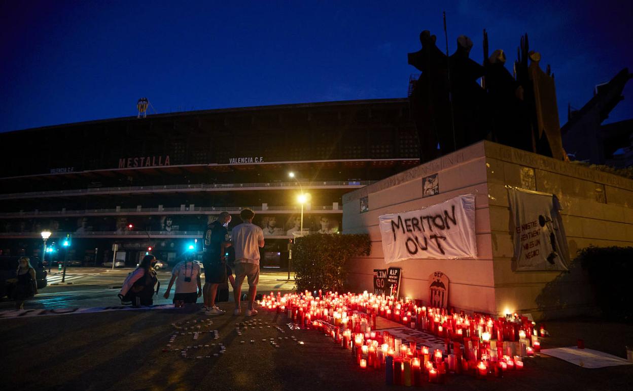 Las velas encendidas en el monumento a la afición, en señal de protesta, escoltan a una pancarta contra Meriton. 