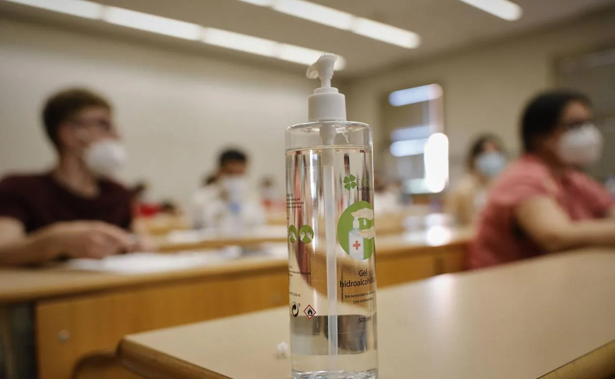 Alumnos en clase ante una botella de gel desinfectante. 