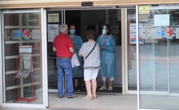 Dos sanitarios niegan la entrada a un centro de Salud en Madrid cerrado por un brote.