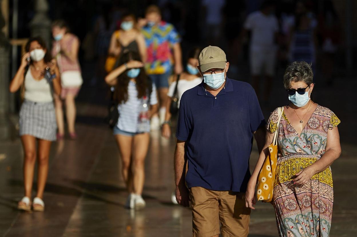 Varias personas caminan por una acera de la calle Xàtiva, todos con mascarilla. iván arlandis