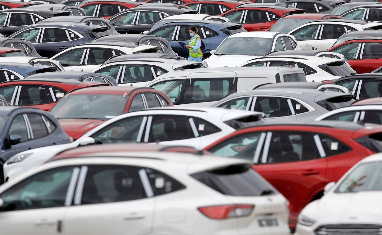 Una trabajadora de Ford camina entre automóviles aparcados en el exterior de la planta en Almussafes.