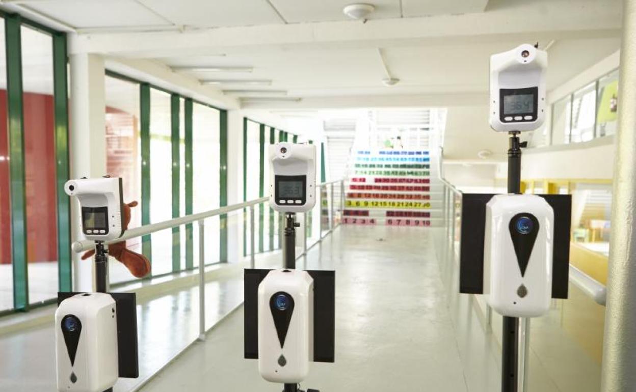 Dispensador de gel hidroalcohólico y medidor de temperatura a la entrada de un colegio. 