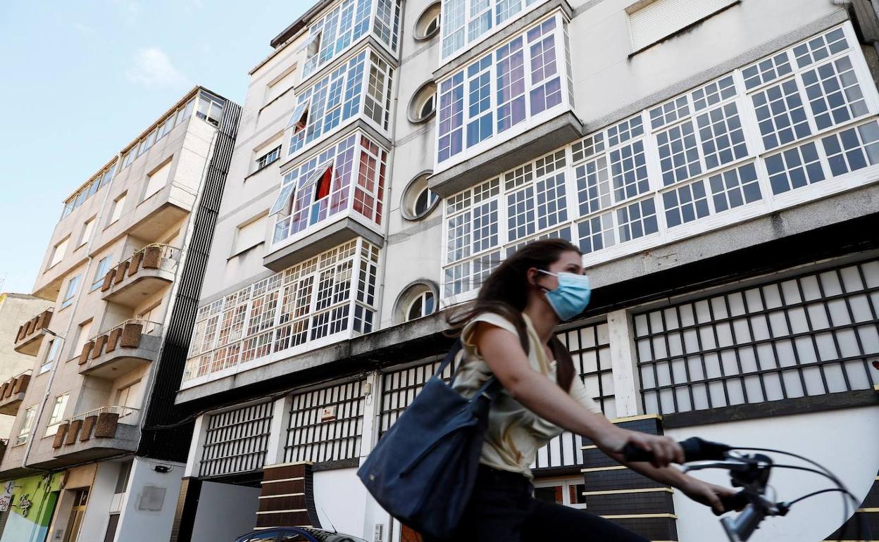 Una joven pasa por delante de un bloque de edificios. 