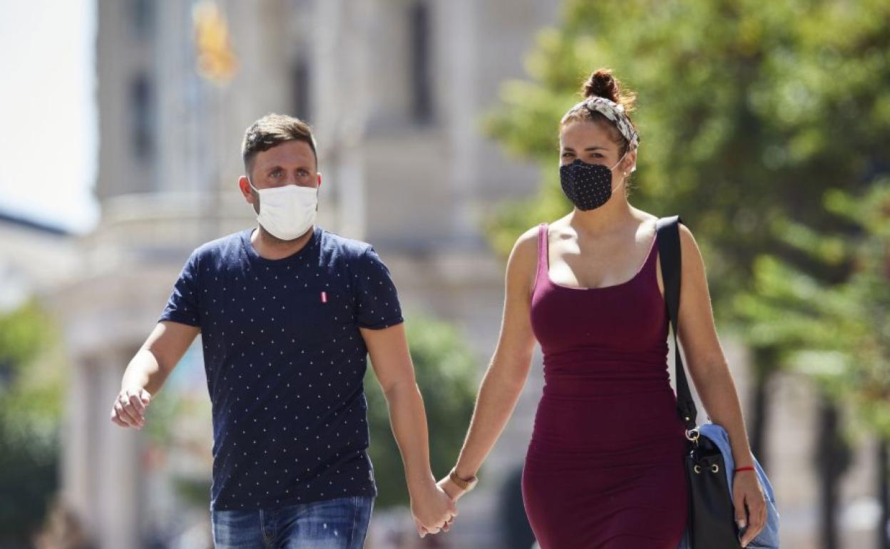 Pareja con mascarilla paseando por Valencia.