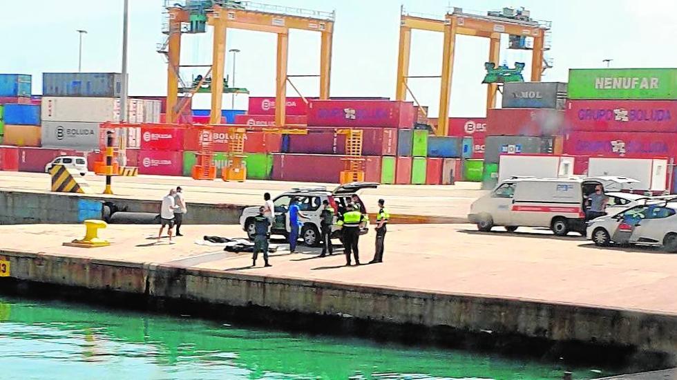 Drama en el puerto. Policías y guardias civiles junto a los cuerpos de los dos polizones fallecidos al arrojarse de un portacontenedores el pasado 7 de agosto en Valencia. 