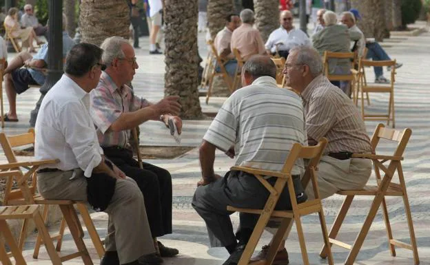 Un grupo de jubilados charlan en un parque. 