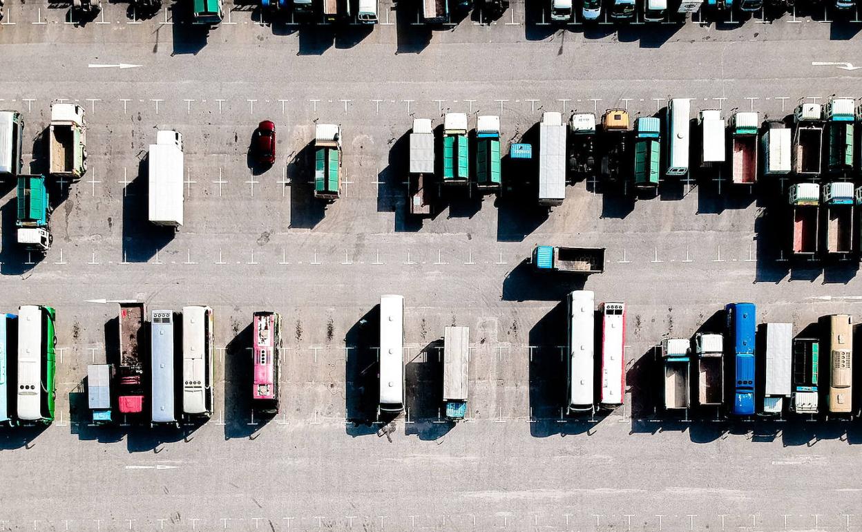 Un gran número de camiones estacionados en un aparcamiento. 