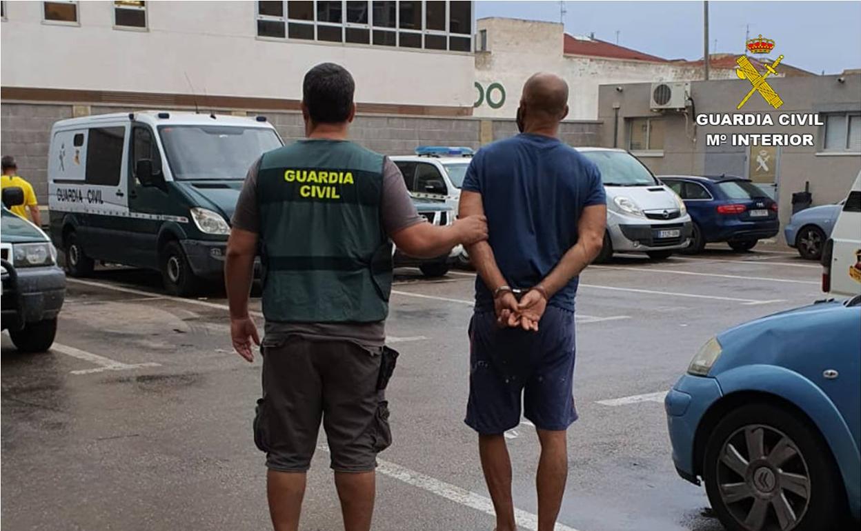 Un agente de la Guardia Civil traslada al detenido esposado. 