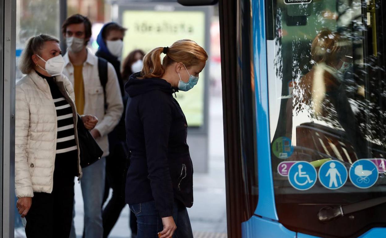 Varias personas con mascarilla suben a un autobús. 