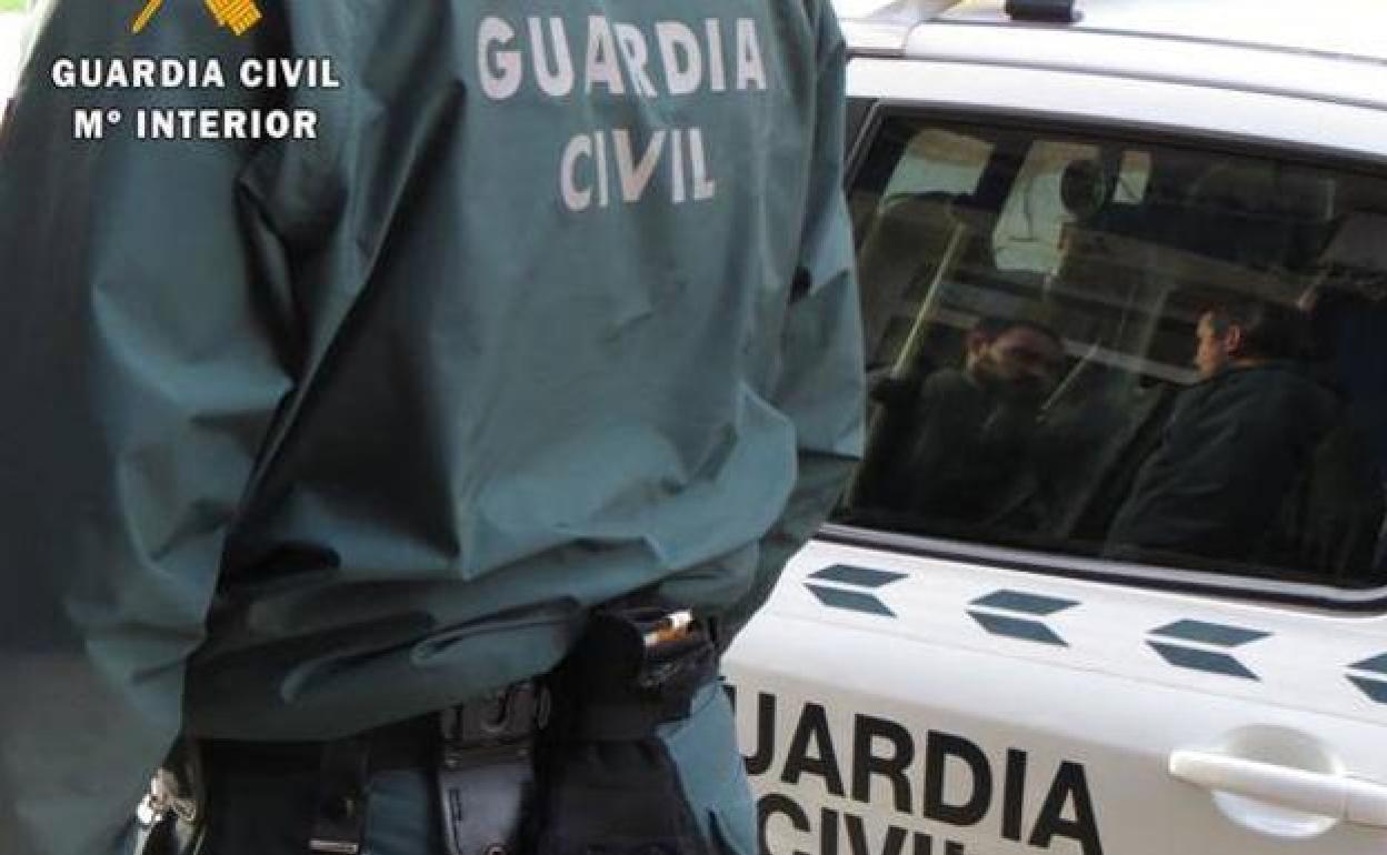 Un guardia ciivl junto a un coche patrulla.