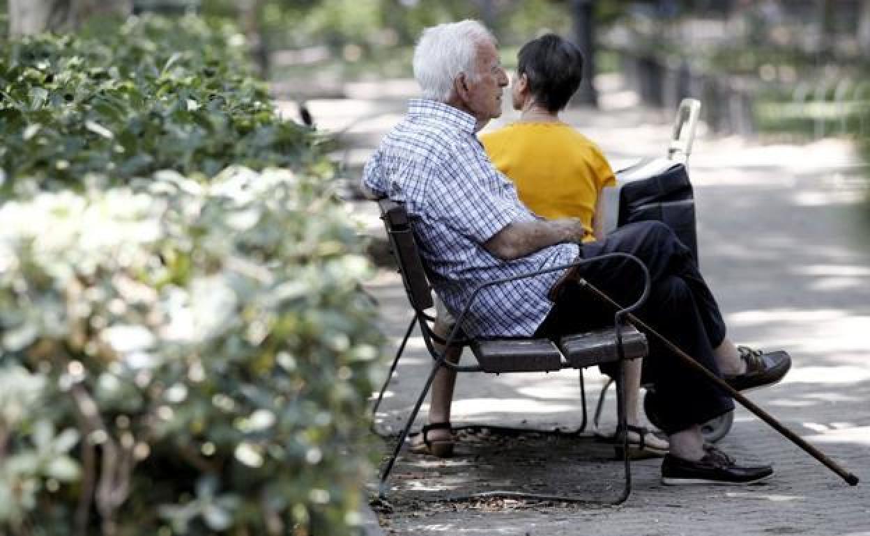 Un jubilado descansa sentado en un banco.