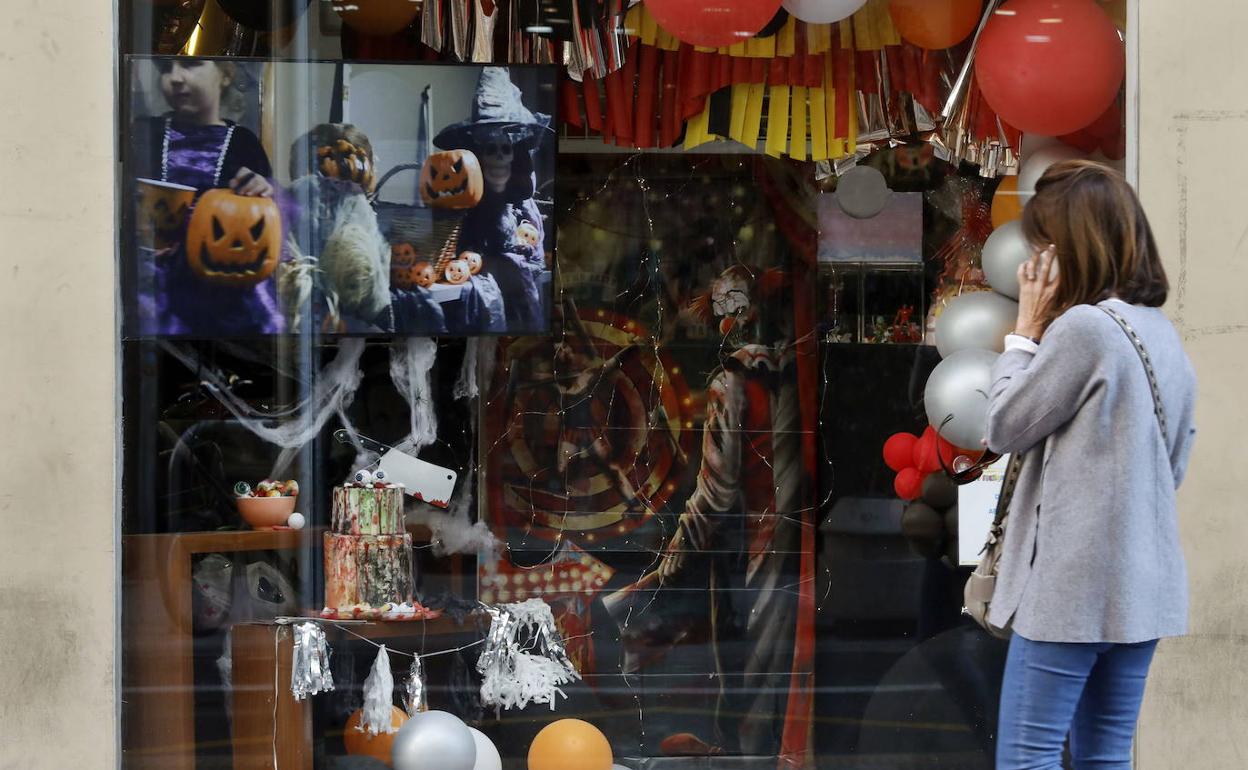 Una viandante observa un escaparate con productos de Halloween. 