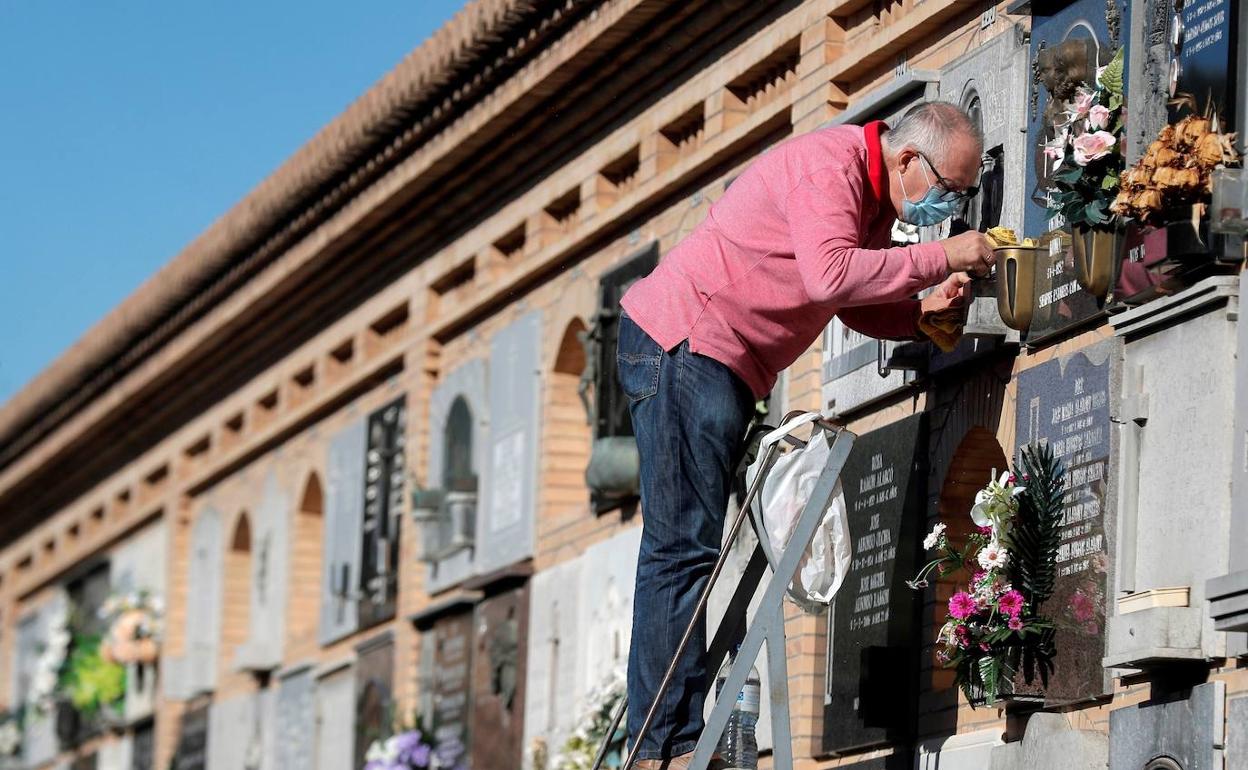 Un familiar arregla una tumba en el cementerio de Valencia. 