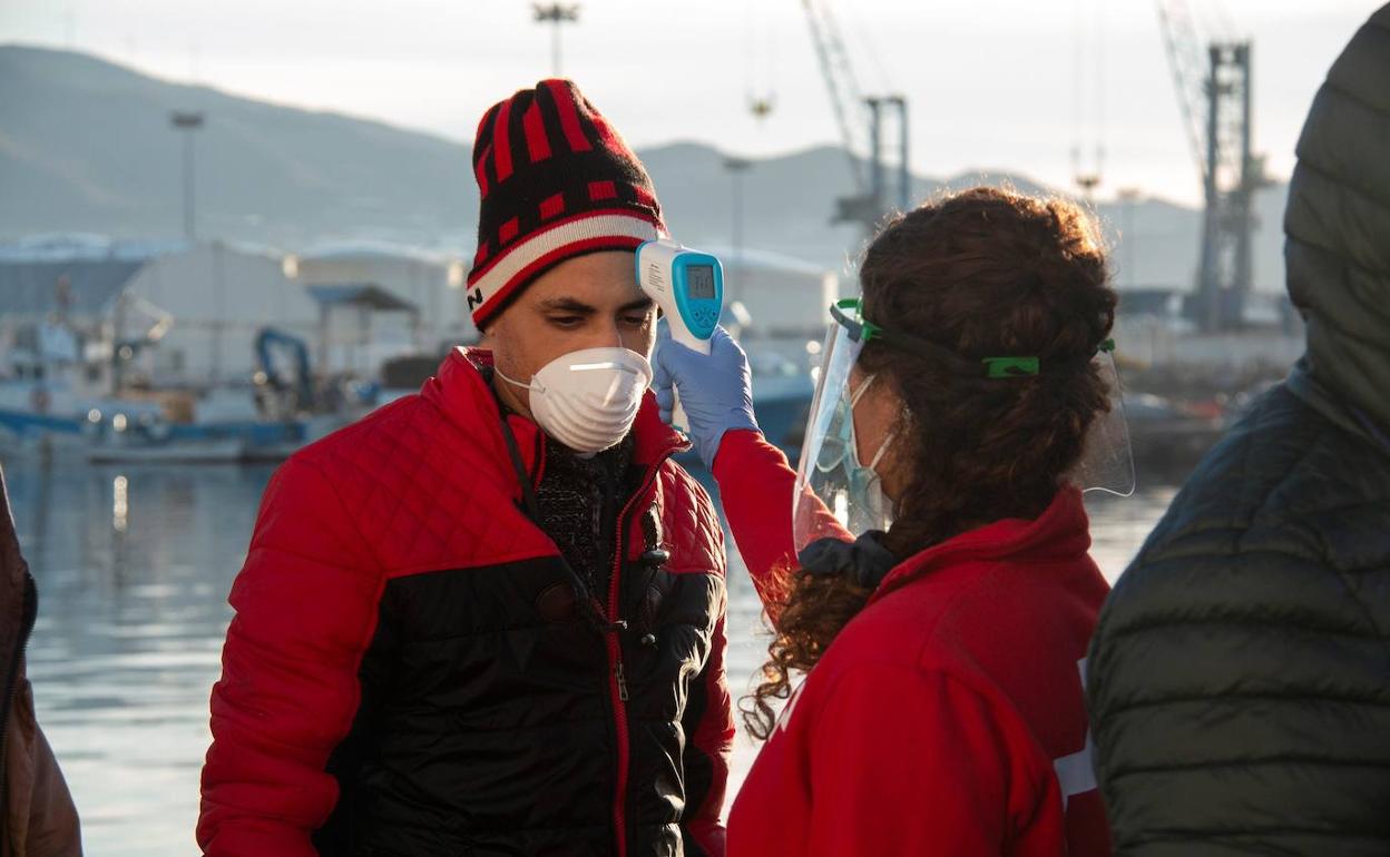 Una sanitaria de Cruz Roja toma la temperatura a uno de los inmigrantes.