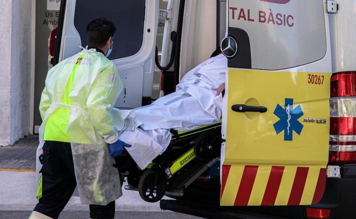 Un sanitario traslada a un paciente de una ambulancia a urgencias del Hospital Clínico de Valencia. 