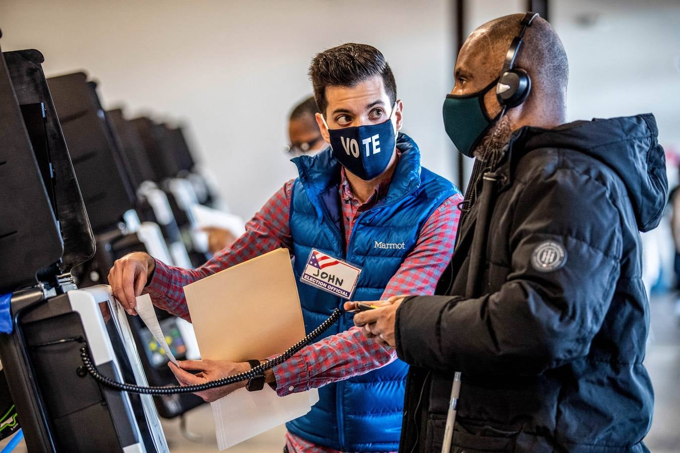 Un trabajador electoral asiste a un votante ciego en uan mesa de Union Market en Washington.